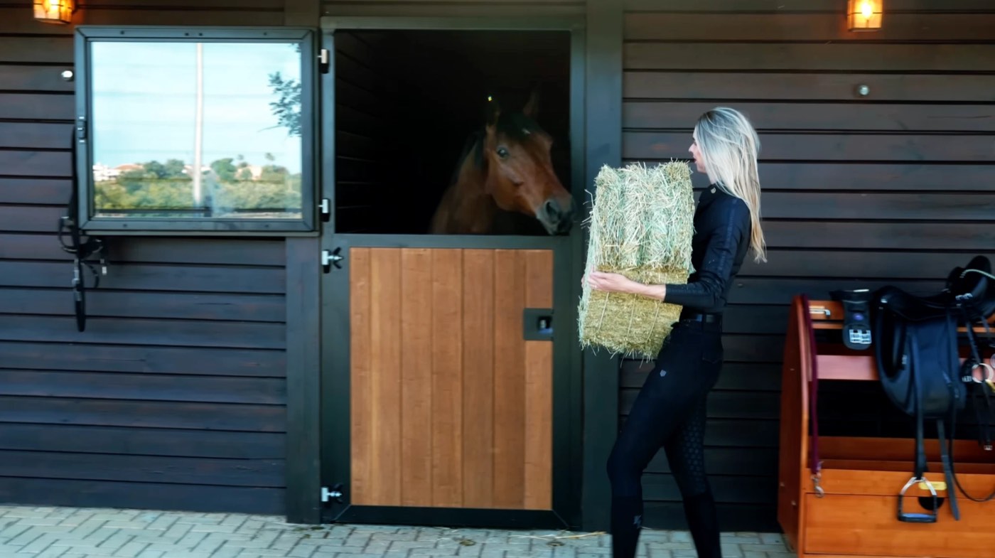 Marlot bringing a bale of hay to her horse at the stable door